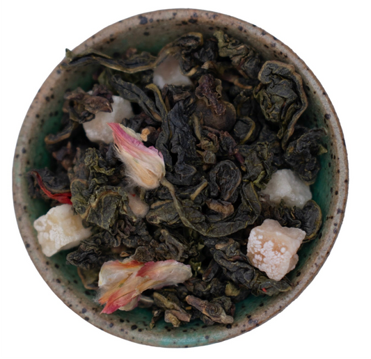 A bowl of loose leaf Sandia Mountain Oolong tea, showcasing the tea leaves and pieces of fruit and petals incorporated into the blend.